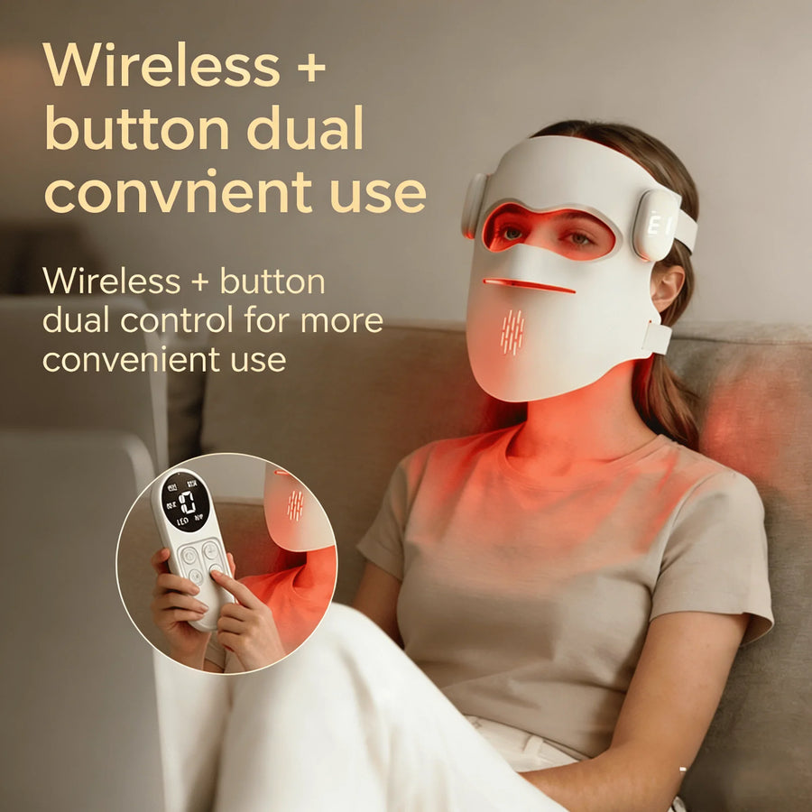 Woman wearing a wireless LED red light therapy face mask with handheld remote, relaxing on sofa.